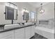 Bathroom featuring double sinks, a bathtub, and marble tiling at 23886 W Harrison Dr, Buckeye, AZ 85326