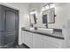 Bathroom featuring double sinks, white cabinets, and a dark-colored door at 23886 W Harrison Dr, Buckeye, AZ 85326