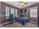 Cozy bedroom featuring a ceiling fan, large windows and a gaming setup at 23886 W Harrison Dr, Buckeye, AZ 85326