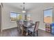 This dining room has a table with four chairs, wood-style flooring, and large windows for natural light at 23886 W Harrison Dr, Buckeye, AZ 85326