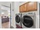 Modern laundry room features front load washer and dryer with cabinets, open to living space at 23886 W Harrison Dr, Buckeye, AZ 85326