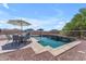 Beautiful backyard pool with dining set, umbrella, and rock waterfall feature at 23886 W Harrison Dr, Buckeye, AZ 85326