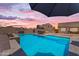Dusk view of the pool with surrounding patio, outdoor dining, and landscaped yard at 23886 W Harrison Dr, Buckeye, AZ 85326