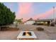 Spacious backyard with brick-paved patio, fire pit, garden boxes and detached structure at dusk at 2726 W Meseto Cir, Mesa, AZ 85202