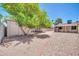 View of the backyard featuring a gravel groundcover, shed, mature trees, and block wall fence at 3444 E Paradise Dr, Phoenix, AZ 85028