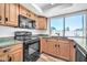A well-lit kitchen with wooden cabinets, black appliances, and a window view at 3444 E Paradise Dr, Phoenix, AZ 85028