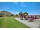 Community playground with green grass, mature trees, and mountain views at 35414 N 32Nd Dr, Phoenix, AZ 85086