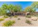 Community entrance sign with desert landscaping, lush plants, and colorful flowers. The sign reads, 