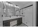 Bathroom featuring double vanity, framed mirror, modern lighting, and tiled shower with glass door at 36602 W San Alvarez Ave, Maricopa, AZ 85138