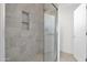 Modern shower with gray tile, glass door, niche, and penny tile flooring at 37504 W Elm Ave, Tonopah, AZ 85354
