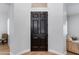 Close up of a stained brown wooden front door with white walls and wood floors at 3804 E Daley Ln, Phoenix, AZ 85050
