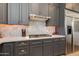 Close-up view of gray kitchen cabinets, a gas range, stainless steel appliances, and marble backsplash at 3804 E Daley Ln, Phoenix, AZ 85050