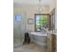 Well-lit bathroom featuring a freestanding tub, a separate glass shower, and a large window at 41916 N 101St N Pl, Scottsdale, AZ 85262