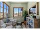 Cozy living room with upholstered armchairs, an ottoman, and a cabinet with desert views from the window at 41916 N 101St N Pl, Scottsdale, AZ 85262