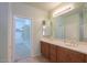 Bright bathroom with double sinks, wood cabinets, large mirror, and walk-in closet at 42360 W Abbey Rd, Maricopa, AZ 85138