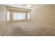 Expansive bedroom boasts plush carpeting, a ceiling fan, and multiple windows for natural light at 42360 W Abbey Rd, Maricopa, AZ 85138