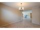 Spacious dining room with beige walls, chandelier, and tiled floor flows into a large living area at 42360 W Abbey Rd, Maricopa, AZ 85138