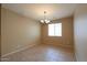 An open dining room is brightly lit by a chandelier and sunlight streaming from a window with tile floors at 42360 W Abbey Rd, Maricopa, AZ 85138
