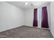 Bright bedroom with neutral carpet, white walls, and dark curtains for cozy relaxation at 43938 W Colby Dr, Maricopa, AZ 85138