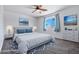 This staged bedroom features calming gray tones, cool blue accents, and a ceiling fan at 43938 W Colby Dr, Maricopa, AZ 85138