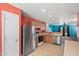 Bright kitchen featuring stainless steel appliances and orange accent wall open to living area at 43938 W Colby Dr, Maricopa, AZ 85138