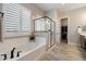Elegant bathroom with a soaking tub, glass-enclosed shower, and shuttered windows for privacy at 5724 E Scarlet St, Mesa, AZ 85215