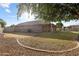 Expansive backyard with a covered patio, lush lawn, mature trees, and a gravel border at 635 S Lanus Dr, Gilbert, AZ 85296