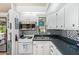 Cozy kitchen featuring white cabinets, stainless steel microwave, dual basin sink and decorative mosaic backsplash at 8700 E University Dr # 1205, Mesa, AZ 85207