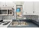 Bright kitchen featuring white cabinets, stainless steel microwave, dual basin sink and decorative mosaic backsplash at 8700 E University Dr # 1205, Mesa, AZ 85207