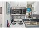 Close-up of kitchen area with stainless steel microwave, stovetop, dual basin sink and decorative backsplash at 8700 E University Dr # 1205, Mesa, AZ 85207