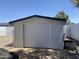 Exterior view of a detached white garage with a closed door in a backyard, complemented by brick-paved driveway at 903 W Jacinto Cir, Mesa, AZ 85210