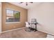 This bedroom is currently being used as an office and features carpeted floors, a ceiling fan and a window at 10529 E Posada Ave, Mesa, AZ 85212