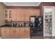 A view of a kitchen with light wood cabinetry, black appliances, and a pantry at 10529 E Posada Ave, Mesa, AZ 85212