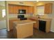 Well-lit kitchen featuring wood cabinets and black appliances, with an island at 12425 W Montebello Ave, Litchfield Park, AZ 85340