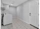 Neutral laundry room featuring a modern washing machine, geometric tiled floor, and a door to the exterior at 13224 N 31St Pl, Phoenix, AZ 85032