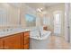 Bright bathroom featuring a soaking tub, separate shower, and dual vanities with cherry cabinets at 14333 W Alvarado Dr, Goodyear, AZ 85395