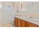 Bathroom featuring double sinks, wood cabinets, a window, and a shower over tub at 14333 W Alvarado Dr, Goodyear, AZ 85395