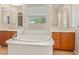Bathroom featuring a soaking tub, dual vanities with cherry cabinets, and large window overlooking the yard at 14333 W Alvarado Dr, Goodyear, AZ 85395
