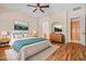 Cozy primary bedroom showcasing hardwood floors, ceiling fan, en-suite bathroom, and stylish furniture at 14333 W Alvarado Dr, Goodyear, AZ 85395