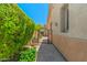 Side yard with brick walkway, wrought iron gate, lush greenery, and a stucco wall at 14333 W Alvarado Dr, Goodyear, AZ 85395
