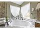Luxurious soaking tub complemented by decorative accents and natural light from the adjacent windows at 1449 W Sherri Dr, Gilbert, AZ 85233