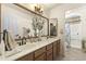 Double sink bathroom vanity with light wood cabinets, neutral countertops, and decorative mirror at 1449 W Sherri Dr, Gilbert, AZ 85233