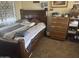 Bedroom with a wooden bedframe, neutral carpet, and decorative pillows, dresser, shelving and accessories at 16696 W Culver St, Goodyear, AZ 85338