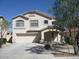 Beige two-story home featuring a two-car garage and covered front porch, landscaped with desert vegetation at 16696 W Culver St, Goodyear, AZ 85338
