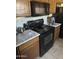 Picture of a kitchen featuring a black stove, microwave, wooden cabinets, and light countertops at 16696 W Culver St, Goodyear, AZ 85338