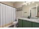 Bathroom with a green vanity, granite countertop, shower with curtain, and modern light fixture at 17560 W Young St, Surprise, AZ 85388