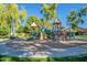 Community playground with multiple slides, climbing structures, and a sand-filled play area under mature trees at 17560 W Young St, Surprise, AZ 85388