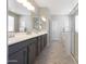Bright bathroom with a double vanity, grey cabinets, stone countertops, decorative mirrors, and a glass shower at 20699 W Ridge Rd, Buckeye, AZ 85396