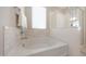 A soaking tub sits beneath a window, complemented by marble tile and a seamless glass shower enclosure at 20699 W Ridge Rd, Buckeye, AZ 85396