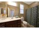 This lovely bathroom features a vanity and a toilet with an artistic shower curtain and large mirror at 20699 W Ridge Rd, Buckeye, AZ 85396